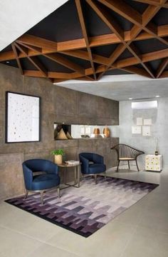 a living room with two blue chairs and a rug on the floor in front of it