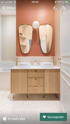 a bathroom with two sinks and mirrors on the wall next to a bathtub in an orange walled room