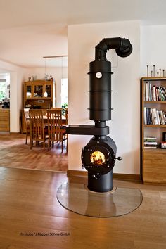 a wood burning stove sitting in the middle of a living room next to a book shelf