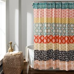 a colorful shower curtain in a bathroom next to a white bath tub with a wicker basket on the floor