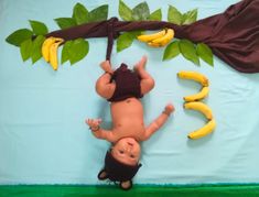 a baby laying on its back in front of some bananas and another child standing up