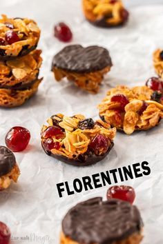 chocolate covered cookies with cranberries and granola toppings on parchment paper that says florentines