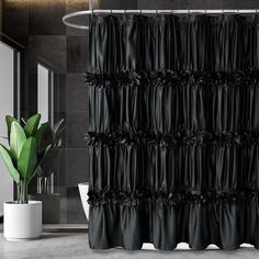 a black shower curtain in a bathroom next to a white toilet and green potted plant