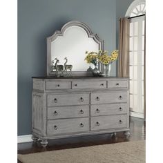 a dresser with a mirror on top of it and flowers in vases next to it