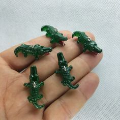 four small green alligator figurines sitting in someone's hand