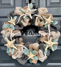 a wreath with starfishs, seashells and burlocks hanging on the front door