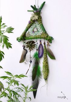 a green and white dream catcher hanging on a wall next to a potted plant