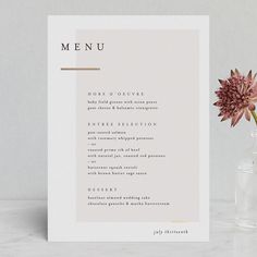 a menu card sitting next to a vase with a flower in it