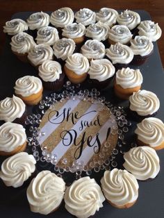 cupcakes with white frosting are arranged on a black platter that says, she said yes