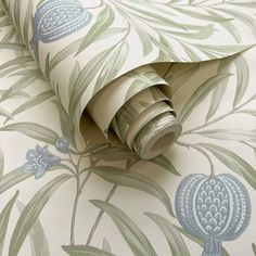 a wallpaper with green leaves and blue flowers on the background is an image of a roll of toilet paper