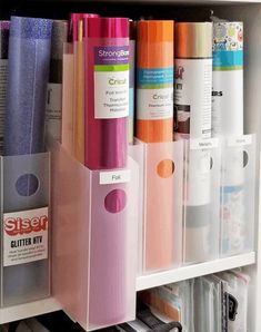 several different colored pens and other office supplies in a white bookcase with clear bins