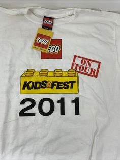 a t - shirt with legos on it that says kids fest 2011 and has stickers attached to the front