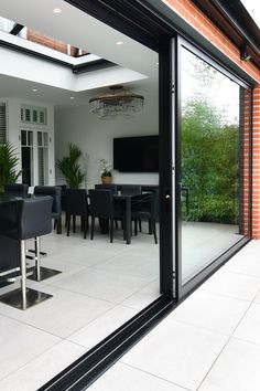 an open glass door leading to a dining room and kitchen area with black chairs on the patio