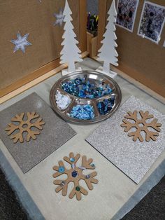 some snowflakes and other decorations are on a table with silver glittered paper