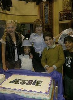 a group of people standing in front of a cake