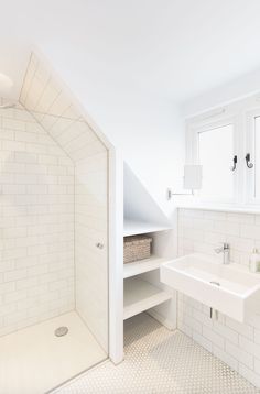 a white tiled bathroom with a walk in shower