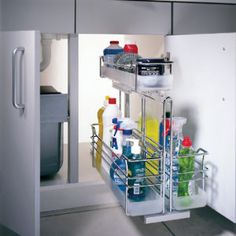 a kitchen sink and shelf with cleaning products in the bottom drawer, next to an open refrigerator door