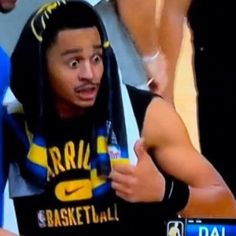 a young man wearing a hoodie and holding a basketball in front of his face