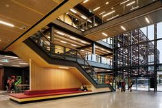 the inside of a large building with stairs and people walking around in front of it