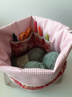 a basket with yarn, scissors and crochet hooks in it sitting on a table