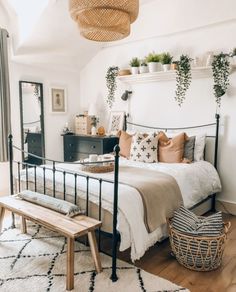 a bed room with a neatly made bed next to a wooden table and mirror on the wall