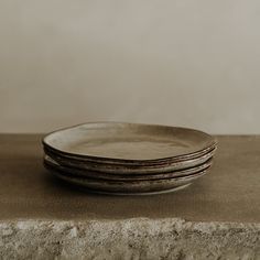 a stack of three plates sitting on top of a stone counter next to a wall