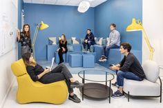 a group of people sitting around in a room with blue walls and yellow accents on the walls