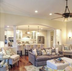 a living room filled with furniture and a ceiling fan in the middle of an open floor plan