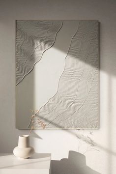 a white vase sitting on top of a table next to a wall mounted mirror in a room