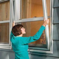 a woman is looking out the window with her hand on the side of the window