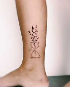 a tattoo on the leg of a woman with a plant in a hour glass vase