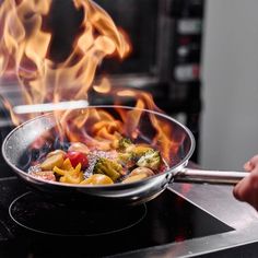 a wok filled with food cooking on top of an open flamed burner