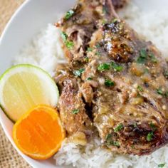 a white plate topped with meat and rice next to an orange slice