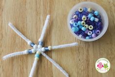 beads are arranged in the shape of a star on a wooden table next to a cup