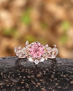 a pink diamond ring sitting on top of a rock