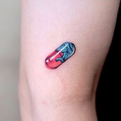 a red and blue pill shaped tattoo on the right side of the leg, with an arrow in it