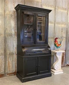 a black cabinet sitting next to a vase with flowers in it on top of a table