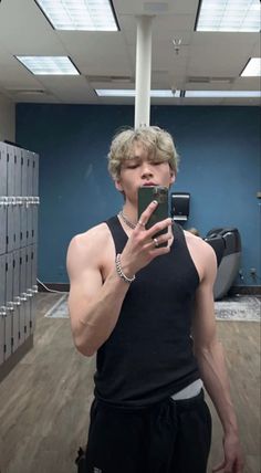 a young man taking a selfie with his cell phone in an empty room filled with lockers