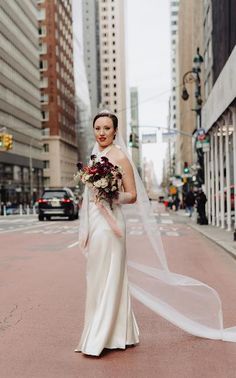 a woman in a wedding dress is standing on the street