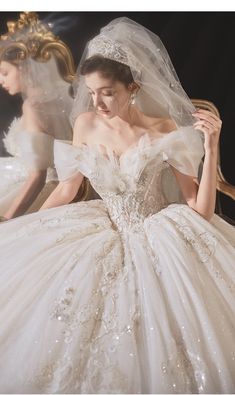 a woman wearing a wedding dress and veil in front of a mirror with her reflection