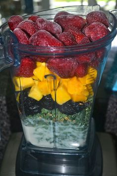 a blender filled with berries, pineapples and kiwis in it