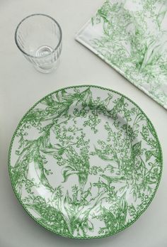 a green and white plate sitting on top of a table next to a glass cup