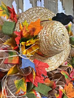 a straw hat with fall leaves on it and a black bird perched on the top