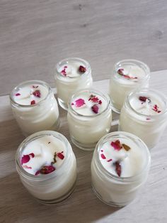 several jars filled with white candles sitting on top of a wooden table next to each other