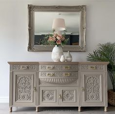 a white vase sitting on top of a dresser next to a mirror