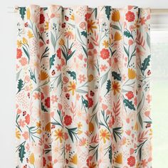 an orange and yellow floral curtain hanging on a window sill in front of a white wall