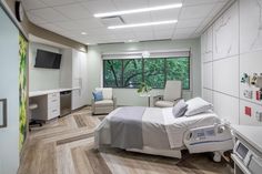 an empty hospital room with a bed, chair and television on the wall in it