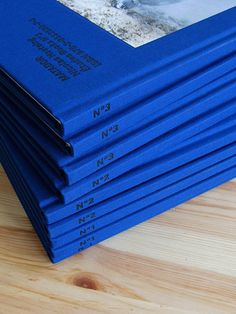 a stack of blue books sitting on top of a wooden table