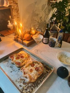 two pizzas sitting on top of a metal pan next to a glass of wine