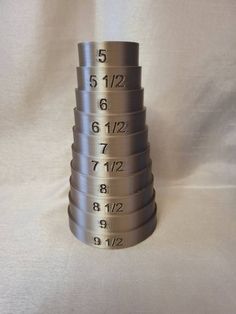 a stack of measuring cups sitting on top of a white table covered in numbers and times